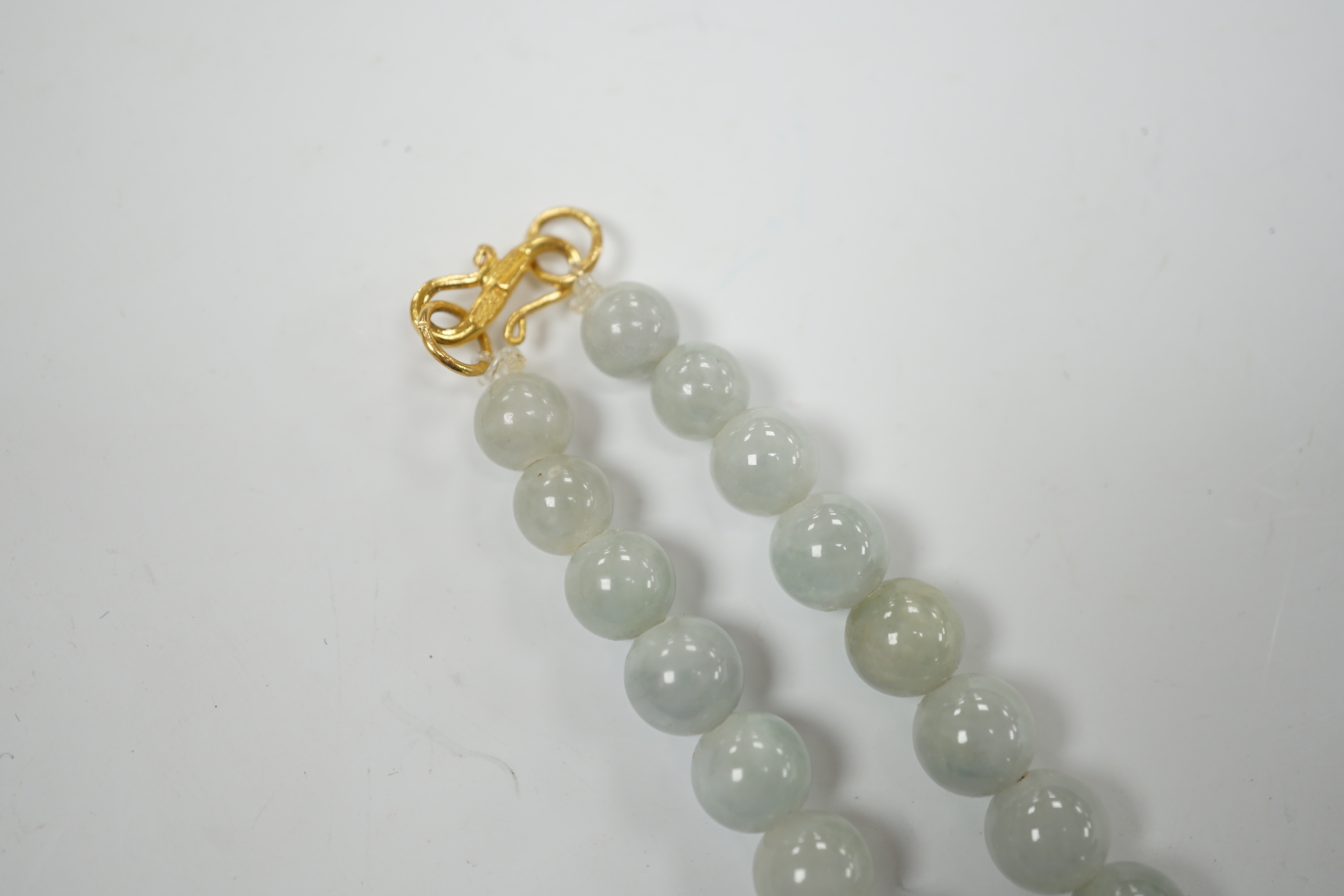 A single strand graduated jade bead necklace, with high carat yellow metal clasp, 46cm.